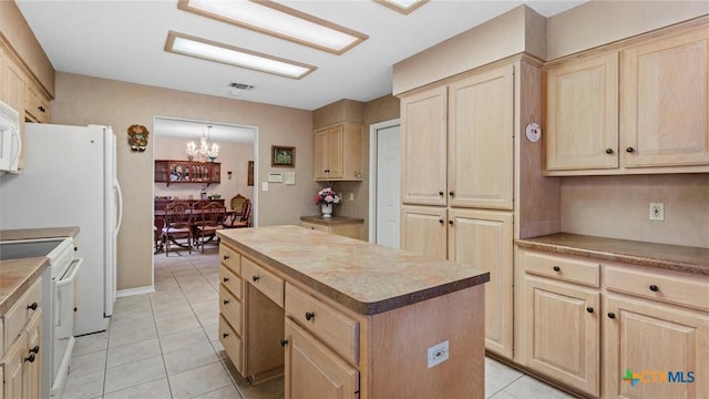 kitchen with light tile patterned floors, white appliances, a center island, and light brown cabinetry