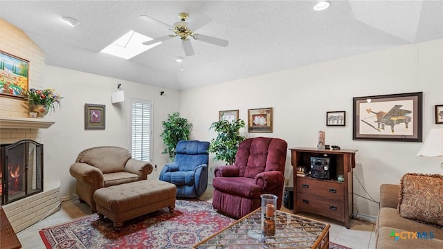 living area featuring vaulted ceiling with skylight, a ceiling fan, light tile patterned flooring, and a fireplace