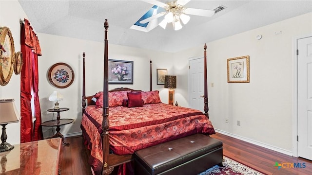 bedroom with visible vents, ceiling fan, baseboards, wood finished floors, and a textured ceiling