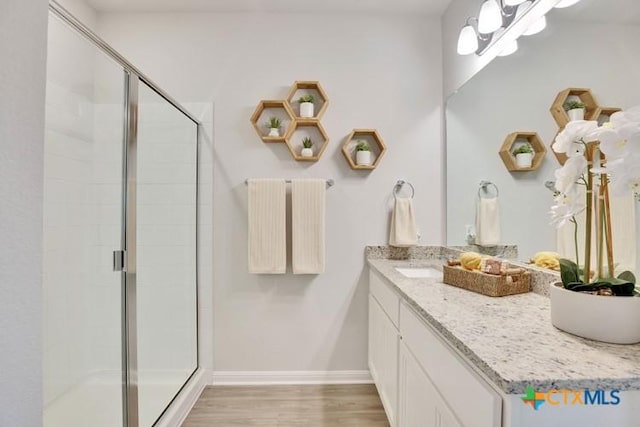 bathroom with hardwood / wood-style flooring, vanity, and a shower with shower door