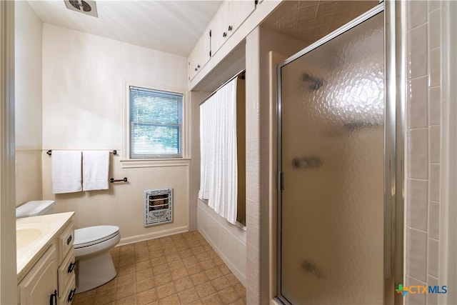 bathroom featuring toilet, vanity, heating unit, and a shower with shower door