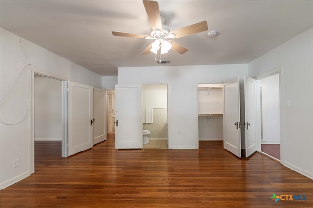 unfurnished bedroom featuring dark wood-type flooring, connected bathroom, ceiling fan, a closet, and a spacious closet