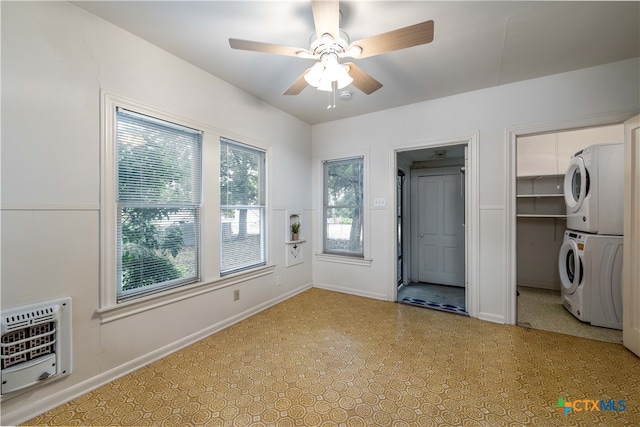 interior space featuring stacked washing maching and dryer, heating unit, and ceiling fan