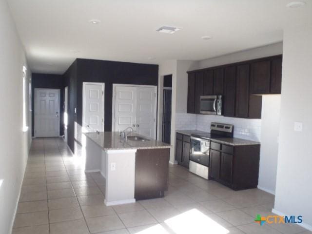 kitchen with sink, dark brown cabinetry, stainless steel appliances, and an island with sink