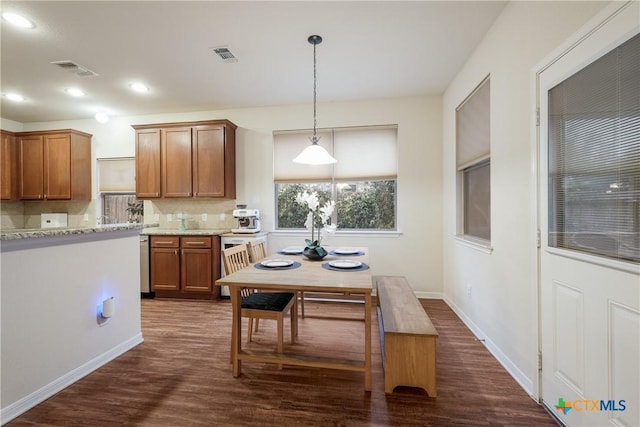 kitchen with dishwasher, decorative backsplash, hanging light fixtures, light stone countertops, and dark wood-type flooring