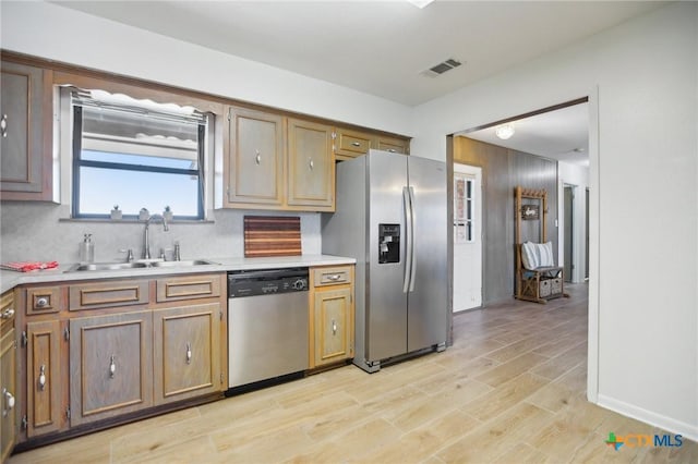 kitchen featuring light wood finished floors, stainless steel appliances, a sink, and light countertops