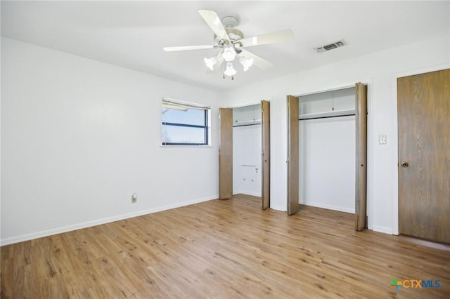 unfurnished bedroom with light wood finished floors, two closets, visible vents, and baseboards