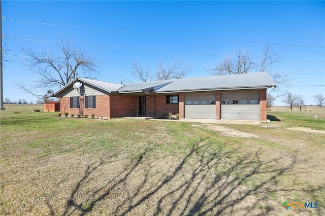 view of front facade with metal roof, an attached garage, brick siding, driveway, and a front lawn