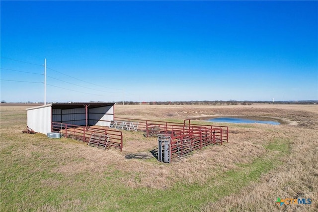 view of yard featuring a water view, a rural view, an exterior structure, and an outdoor structure