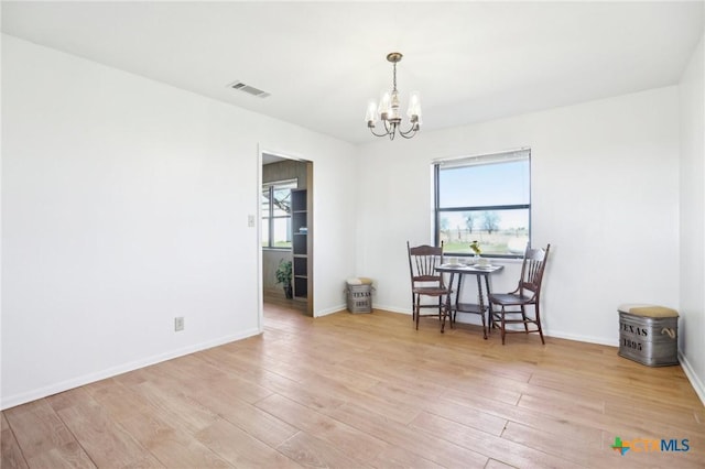 unfurnished dining area with baseboards, visible vents, an inviting chandelier, and wood finished floors