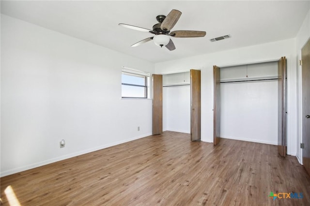 unfurnished bedroom with light wood-style floors, visible vents, baseboards, and two closets