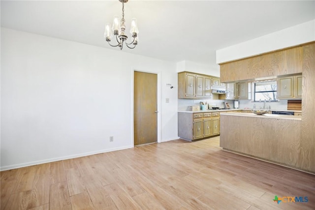 kitchen featuring baseboards, light countertops, light wood-type flooring, under cabinet range hood, and a chandelier