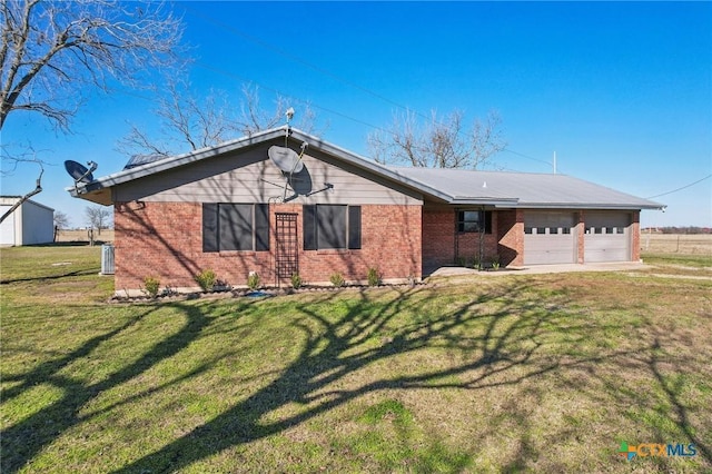 view of front of house featuring an attached garage, central AC, brick siding, driveway, and a front lawn