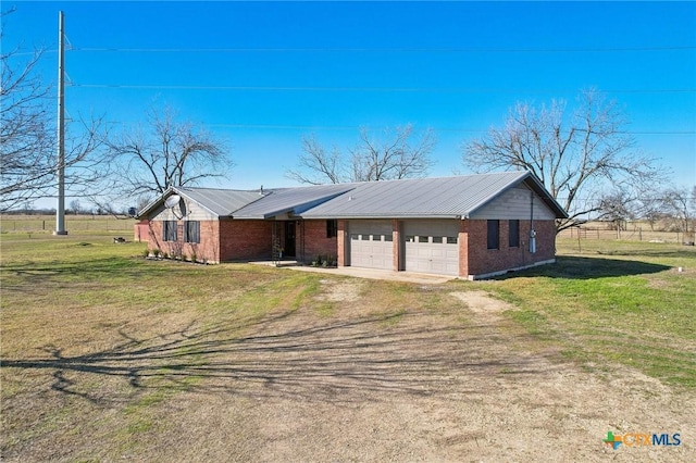 view of front of home featuring a front yard, metal roof, brick siding, and driveway