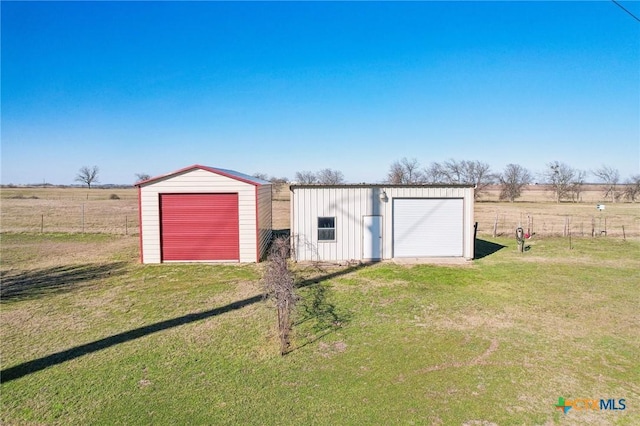 view of outdoor structure with an outbuilding, a rural view, and fence