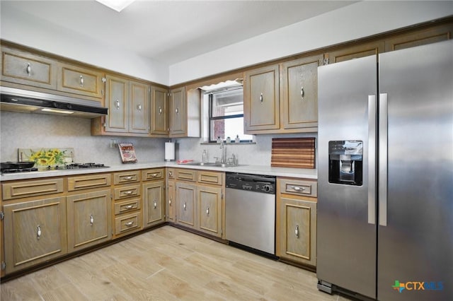 kitchen featuring under cabinet range hood, a sink, light wood-style floors, light countertops, and appliances with stainless steel finishes