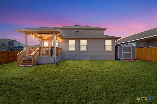 back house at dusk with a storage unit and a yard