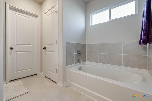 bathroom with tile patterned floors and a tub to relax in