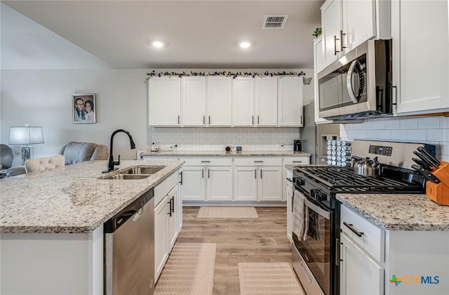 kitchen featuring sink, tasteful backsplash, stainless steel appliances, light hardwood / wood-style floors, and white cabinets