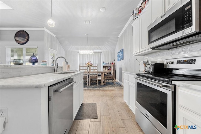 1211 Liberation Ln, Copperas Cove, TX 76522 - kitchen featuring stainless steel appliances, light wood-style floors, white cabinets, tasteful backsplash, and decorative light fixtures