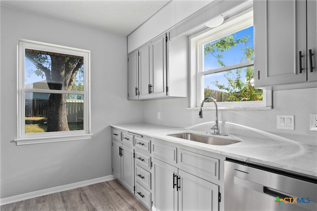 kitchen featuring light stone counters, a textured ceiling, sink, light hardwood / wood-style floors, and dishwasher