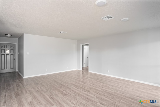 spare room with light wood-type flooring and a textured ceiling