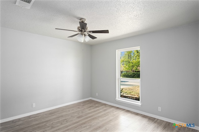 unfurnished room with light wood-type flooring, a textured ceiling, ceiling fan, and plenty of natural light