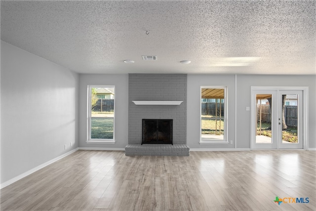 unfurnished living room with a textured ceiling, light hardwood / wood-style floors, and a fireplace