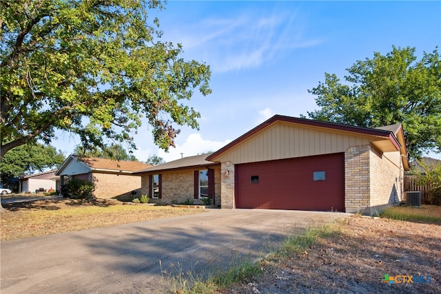 single story home featuring central air condition unit and a garage