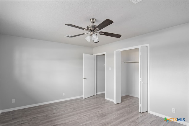 unfurnished bedroom with ceiling fan, a textured ceiling, a closet, and light wood-type flooring