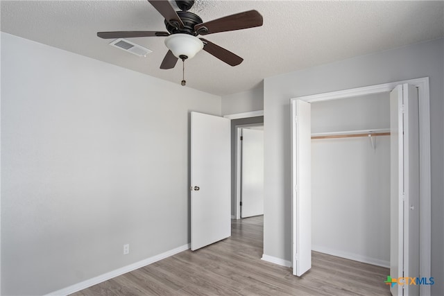 unfurnished bedroom with a textured ceiling, light wood-type flooring, ceiling fan, and a closet