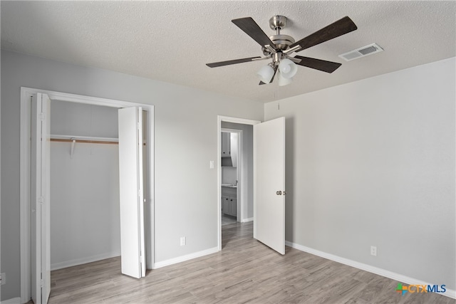 unfurnished bedroom with ceiling fan, a textured ceiling, a closet, and light hardwood / wood-style flooring