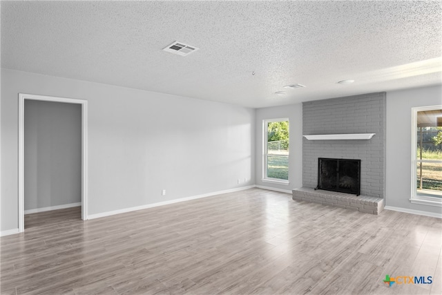 unfurnished living room featuring a wealth of natural light, a textured ceiling, and light hardwood / wood-style flooring