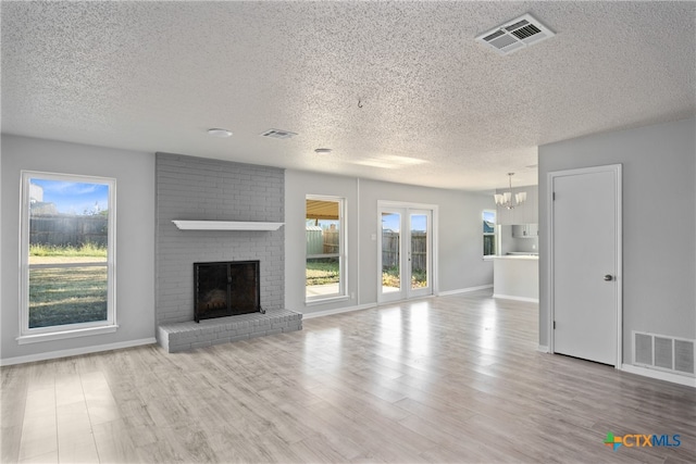 unfurnished living room featuring a fireplace, light hardwood / wood-style flooring, and a textured ceiling