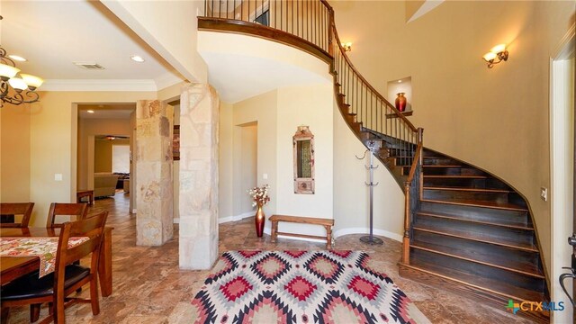 stairway featuring a chandelier, crown molding, baseboards, stone finish flooring, and a high ceiling