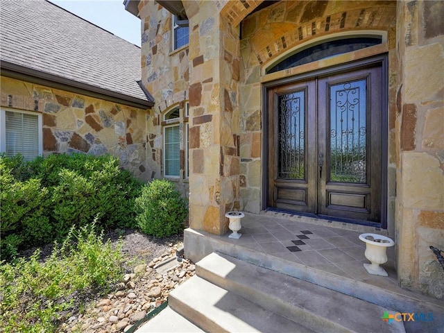doorway to property featuring stone siding and french doors