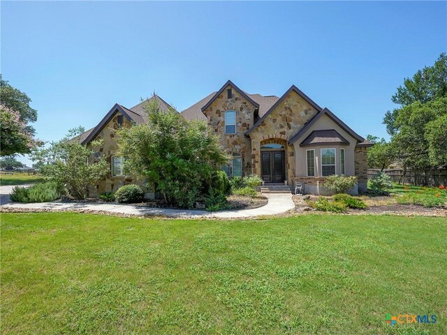 view of front facade featuring stone siding, a front lawn, and french doors