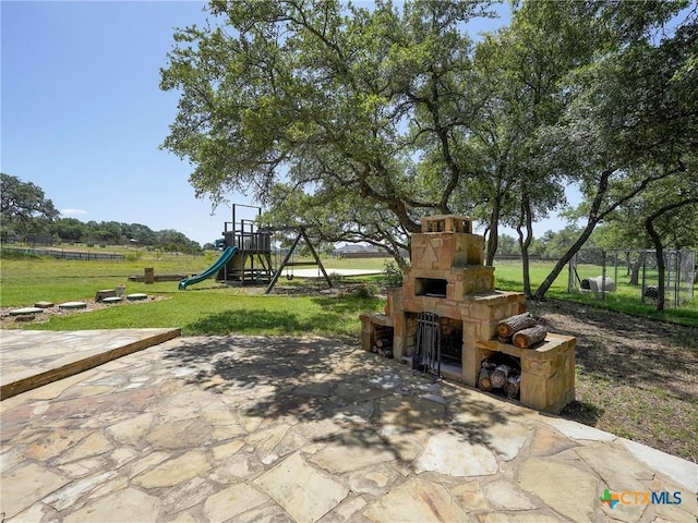 view of patio / terrace with an outdoor stone fireplace and a playground