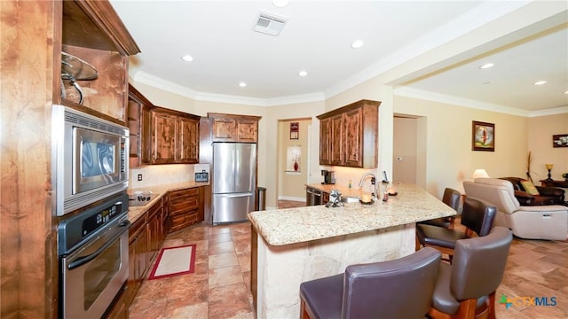 kitchen featuring stainless steel appliances, a peninsula, a sink, open floor plan, and a breakfast bar area