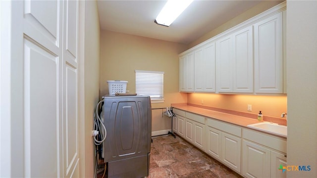 clothes washing area featuring cabinet space, stone finish floors, and baseboards