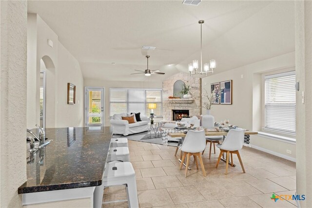 834 Wall St, New Braunfels, TX 78130 - dining area featuring a fireplace, plenty of natural light, light tile patterned flooring, ceiling fan, and vaulted ceiling