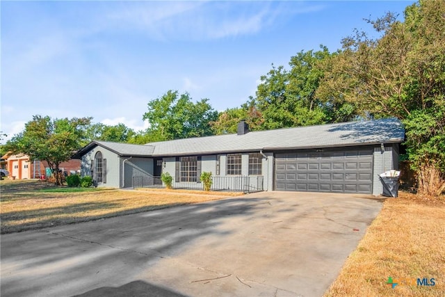 ranch-style house featuring concrete driveway, a chimney, and an attached garage