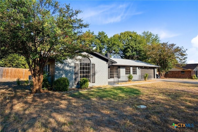 ranch-style house featuring a garage, brick siding, fence, driveway, and a front yard