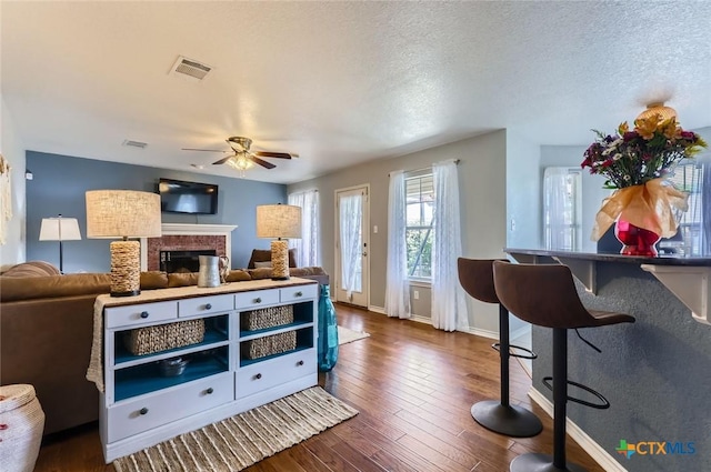 4201 Breckenridge Dr, Killeen, TX 76542 - living area featuring ceiling fan, a brick fireplace, dark wood-style floors, and a textured ceiling
