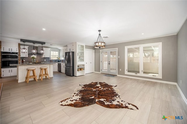 living room with a chandelier, french doors, and baseboards