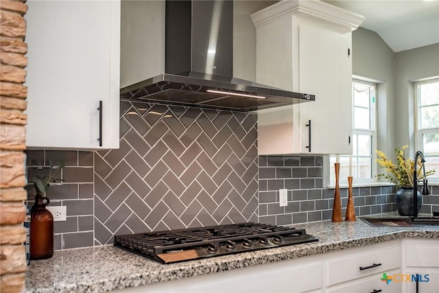 kitchen with black gas cooktop, white cabinets, a sink, and wall chimney range hood