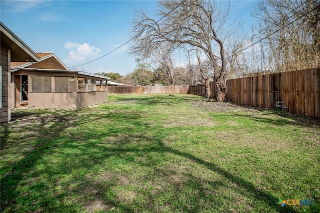 view of yard featuring a fenced backyard and a sunroom