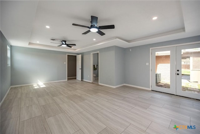 empty room featuring recessed lighting, baseboards, a tray ceiling, and french doors