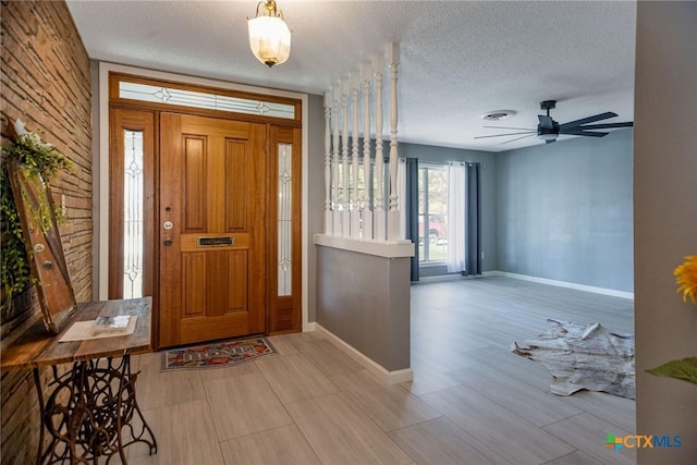 foyer with a ceiling fan, baseboards, visible vents, and a textured ceiling