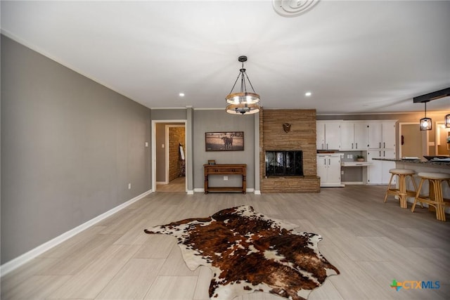 living area with ornamental molding, recessed lighting, a stone fireplace, and baseboards